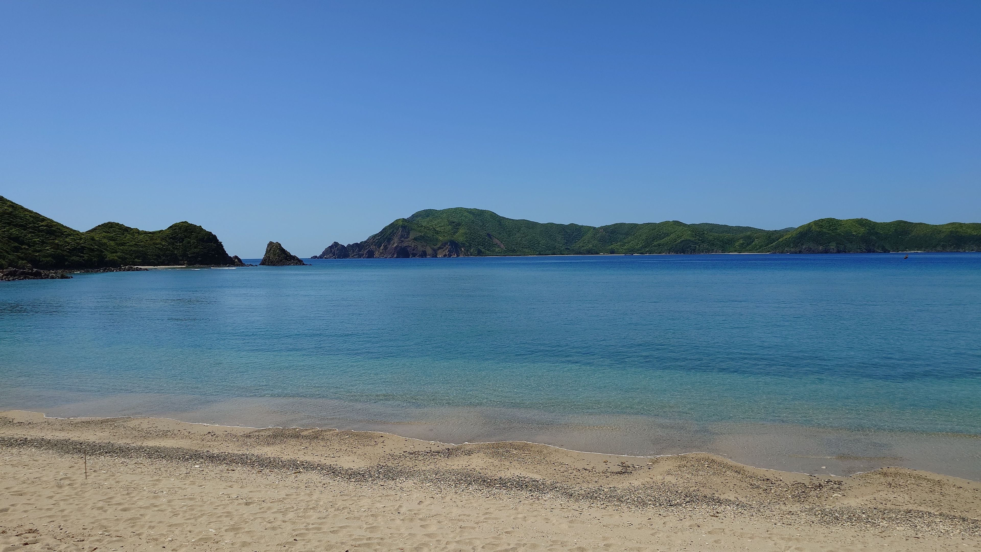 The wide sandy expanse of Yadorihama Beach and the Amami Blue sea