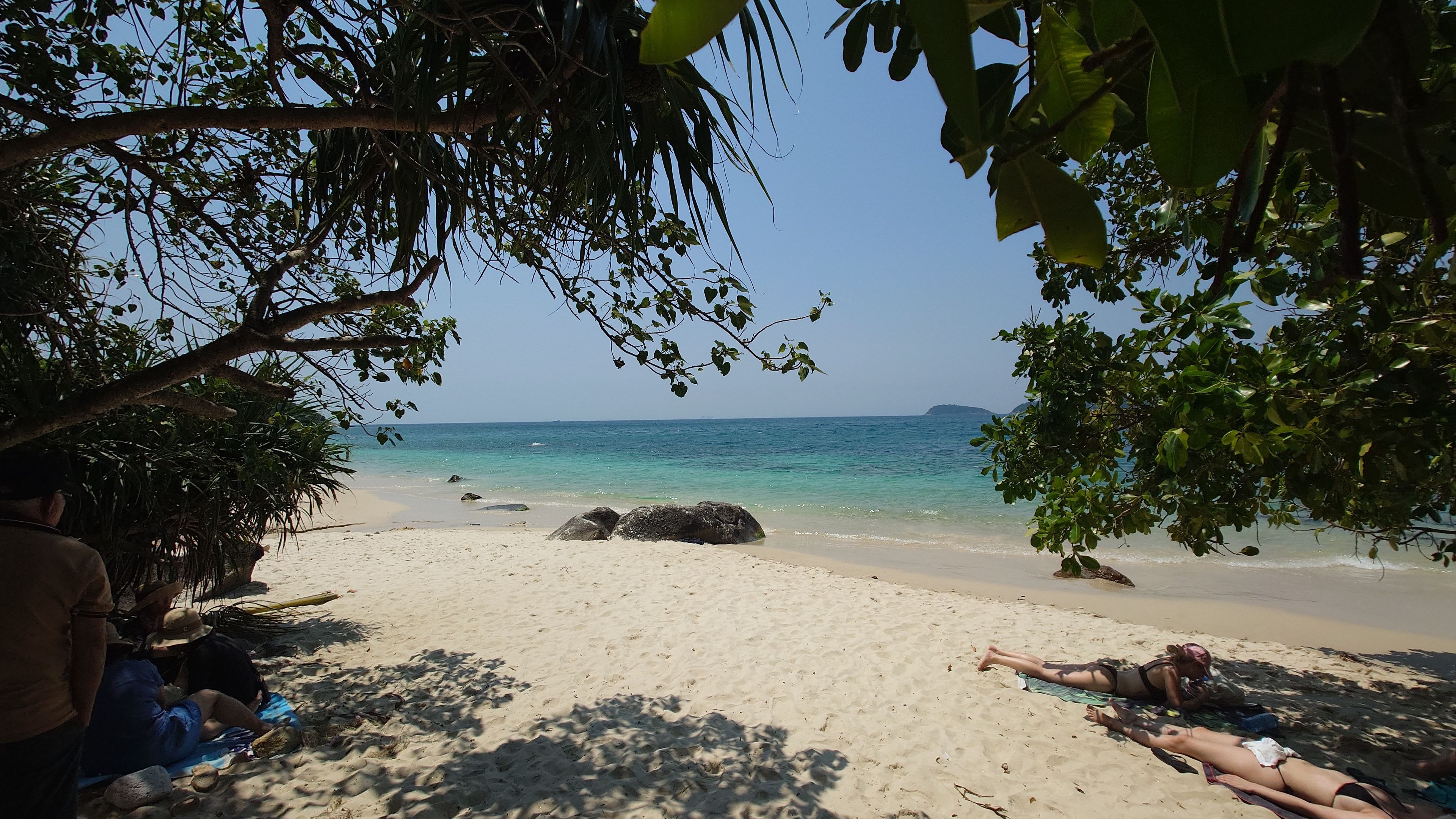 道路からビーチへ。木々の合間からのぞく XEP Beach の砂浜と海