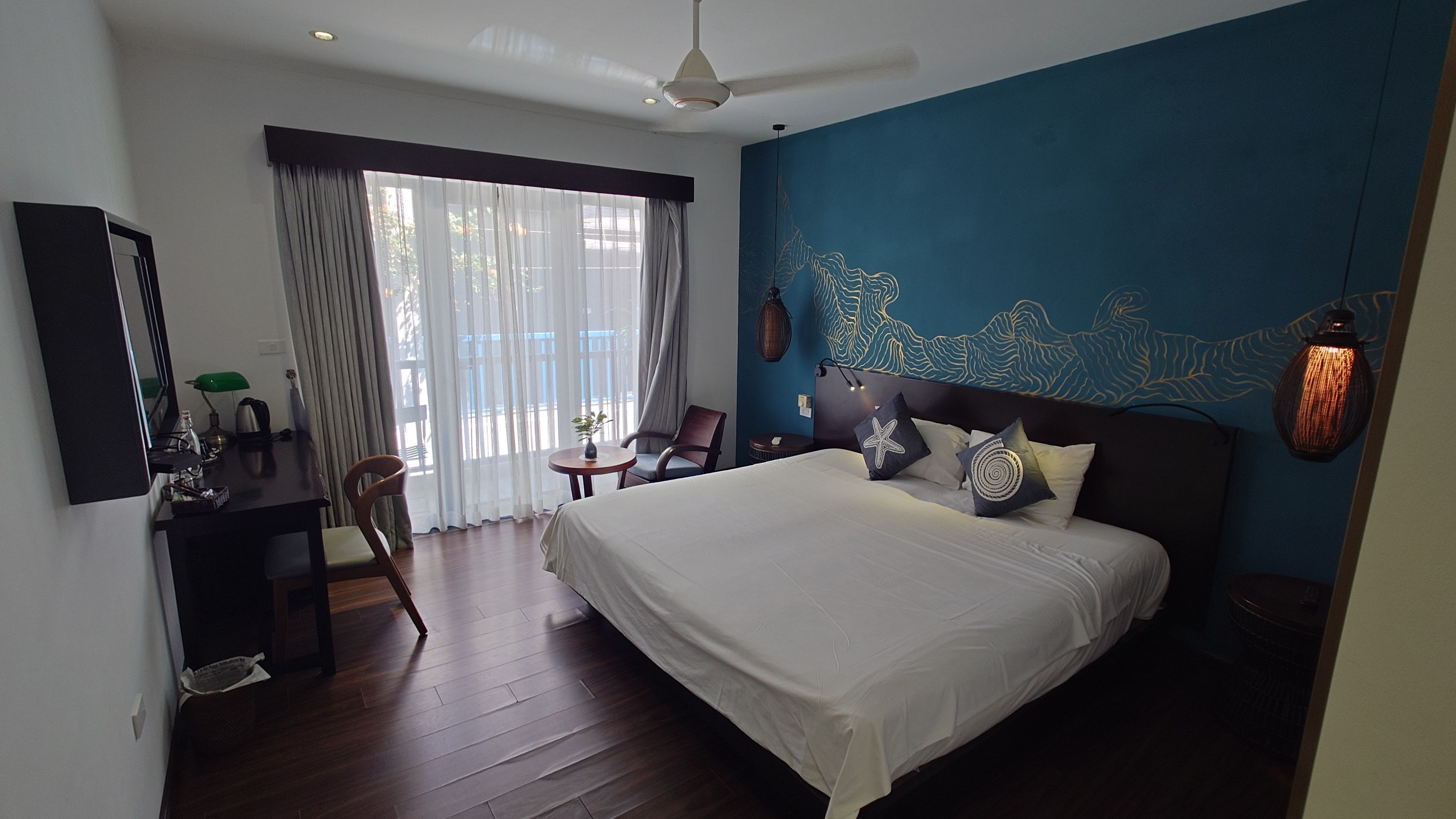 清潔感あふれる客室。天井のファンが機能的で、心地よい風を感じながらリラックスできる空間。