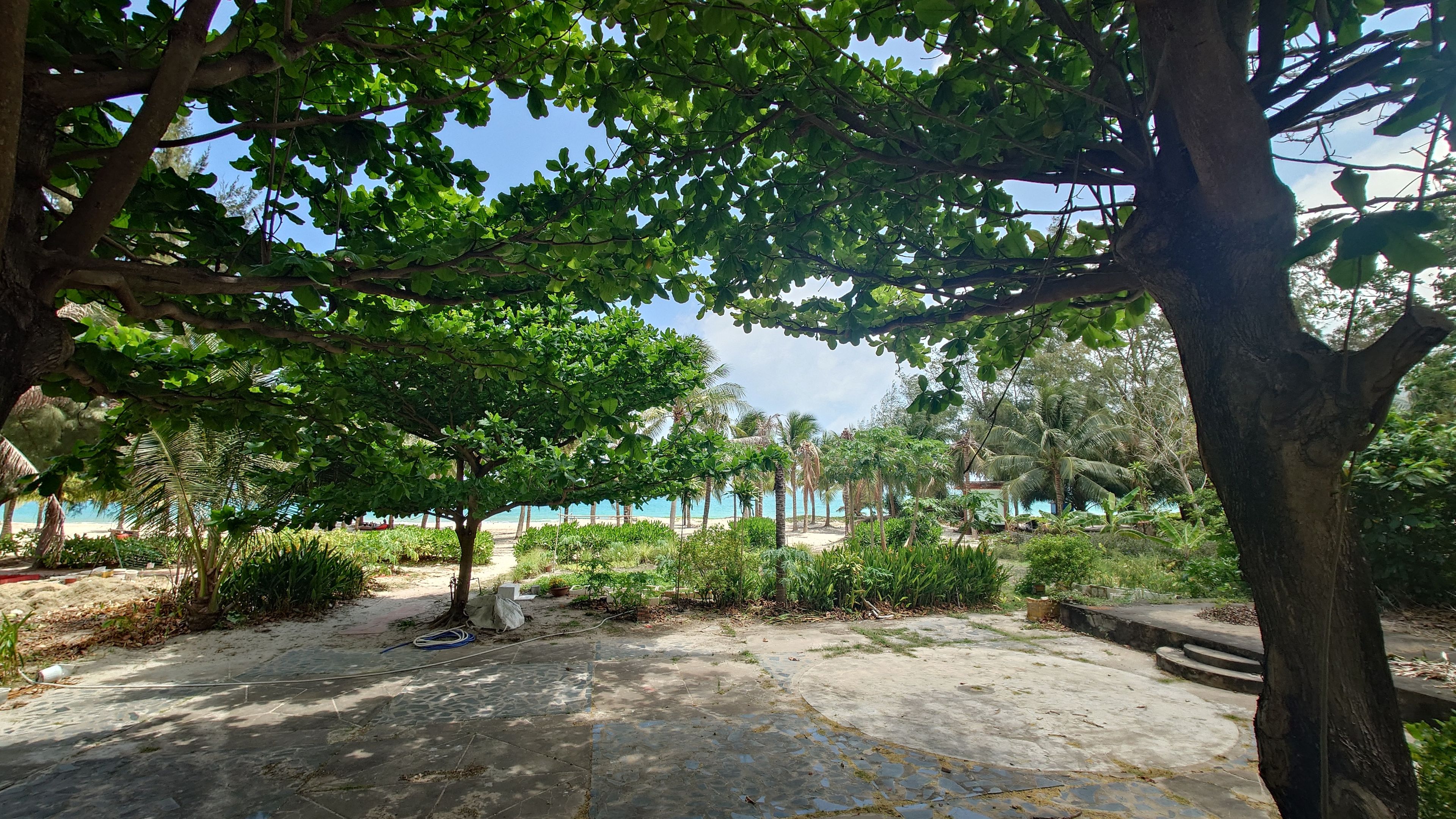 タンソンニャット：客室の前に広がる開放的な緑の中庭と、その先に続くアンハイビーチの海