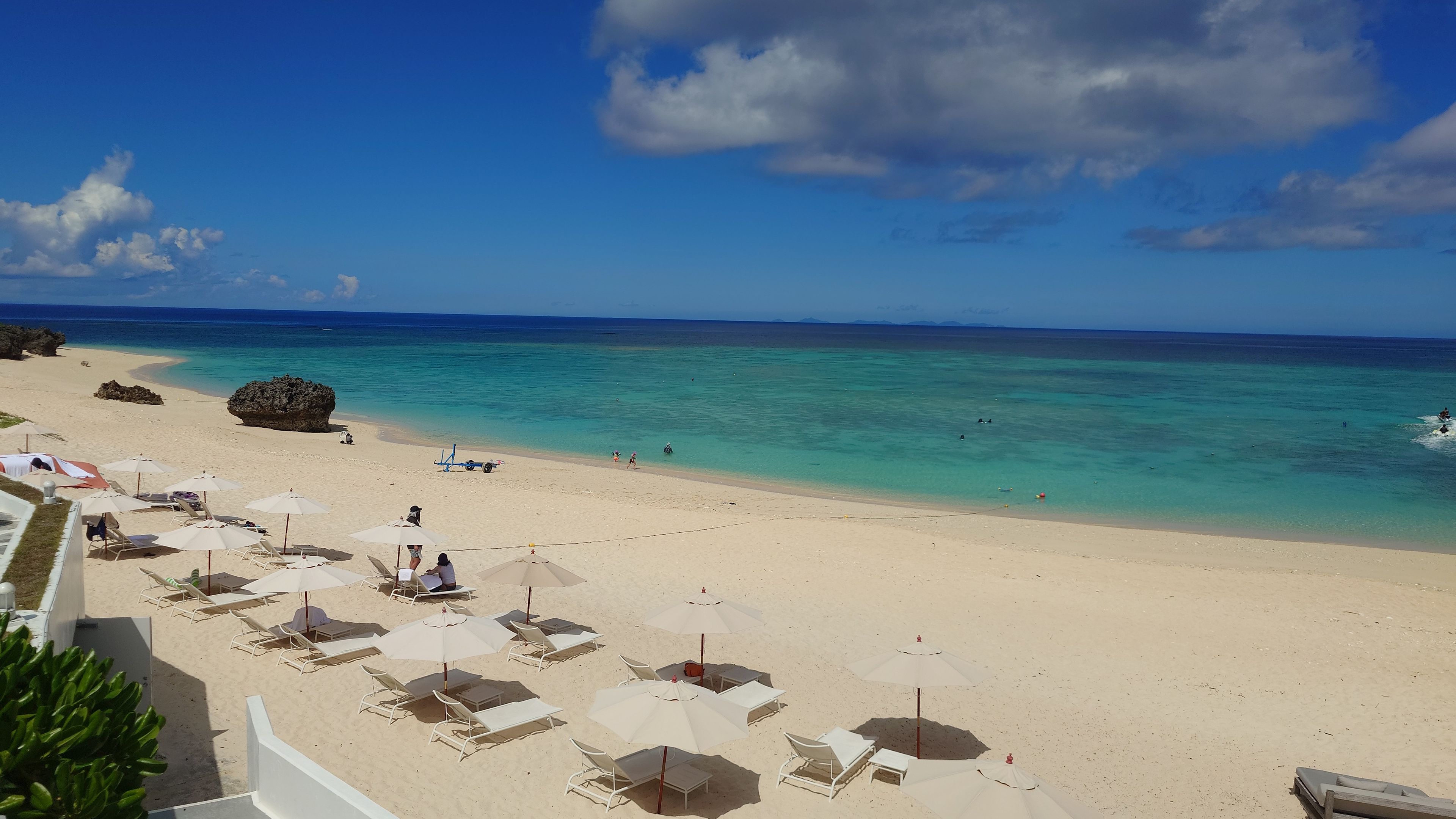 White beach umbrellas and loungers on the beautiful sandy beach adjacent to Pricia Resort Yoron.